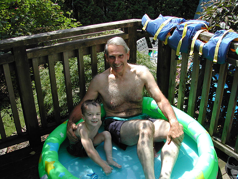Todd and Dad sit in the kiddie pool.