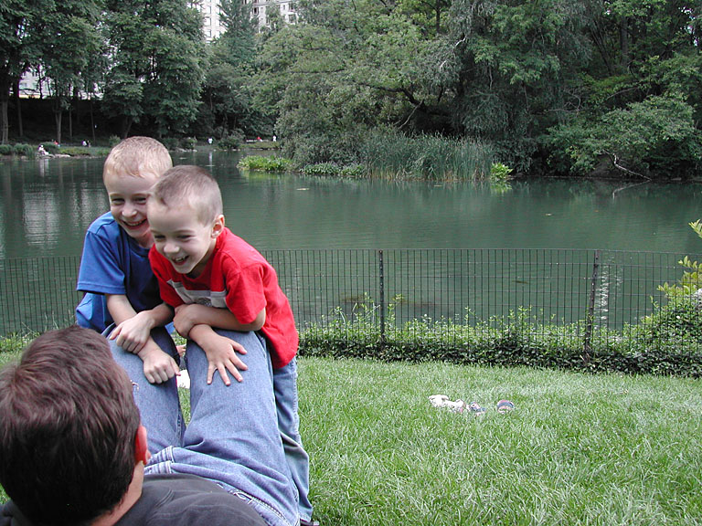Joel and Todd lean on Alan's knees as he relaxes at Central Park.