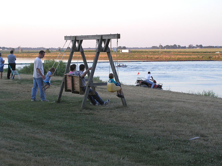 Chad pushes Sarah on the swing.  Todd waits for his turn.