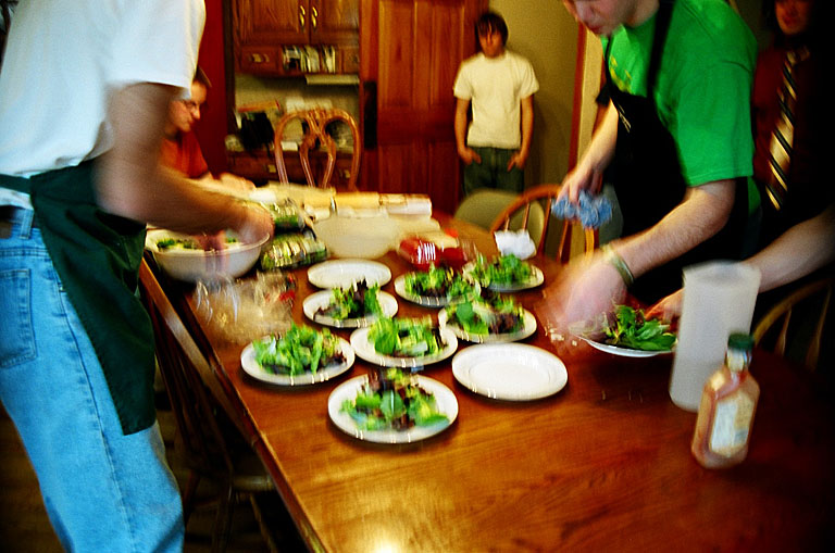 Dan shows Mark and Kyle how he wants the salads made.