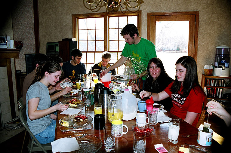 Everyone enjoying a late breakfast of pancakes and waffles.