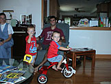 Mom, Joel and Dan watch as Todd takes the new tricycle for a spin.