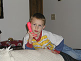 Joel lounges on the sofa with his phone in hand.