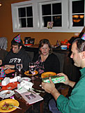Dan is distracted by his pie, while Jodie watches Alan open up a birthday gift.