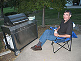 Dennis is in his element, sitting by the grill drinking some coffee.
