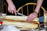 Mark cuts open the bread to stuff them with butter and cheeses.