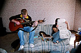 Mark plays the guitar while Katy reads the morning comics.
